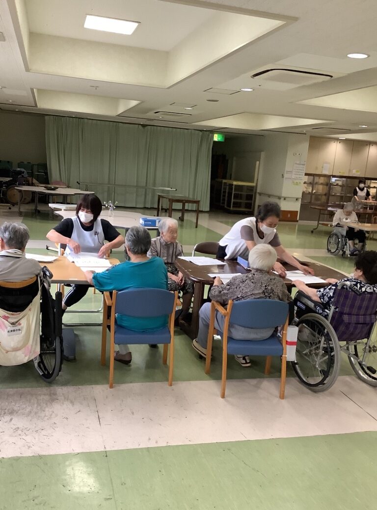 介護施設でスタッフが高齢者入居者とテーブルでレクリエーション活動を行っている風景
