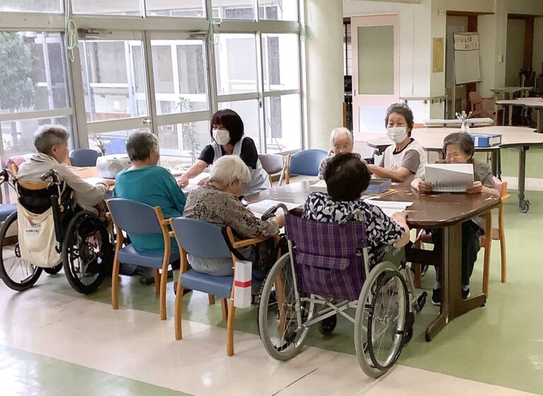 介護施設の共用スペースで入居者がスタッフと共にレクリエーション活動を行っている風景